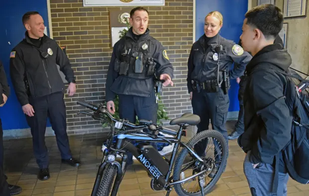 A police officer handing a recovered bicycle back to a smiling young man