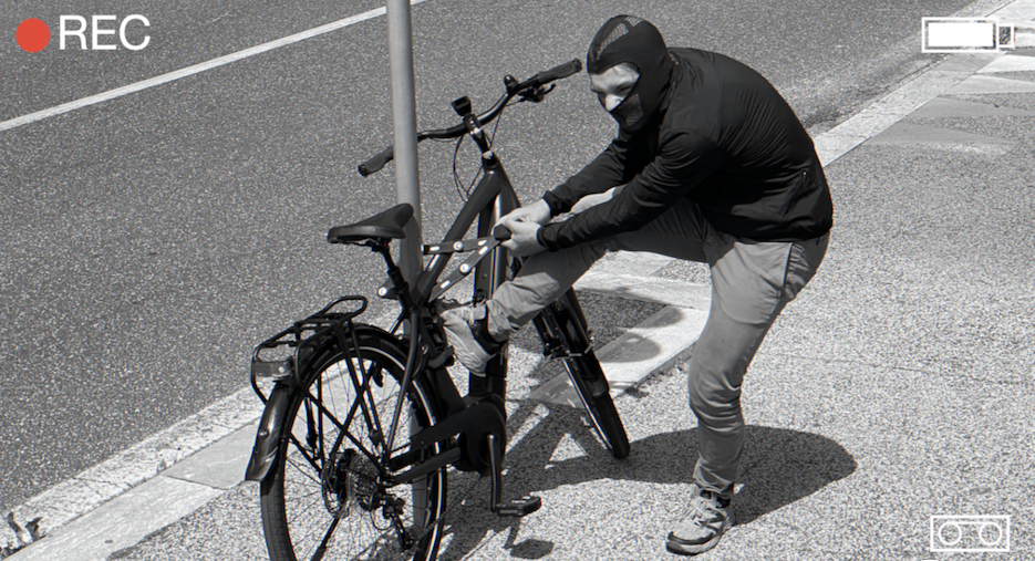 A thief wearing a hoodie stealing a bicycle, caught in the act of cutting the bike lock with bolt cutters, in an urban street setting